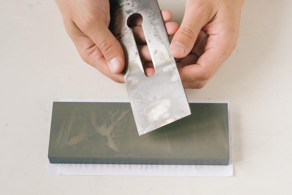 Hands sharpening a knife on a “800” grit whetstone